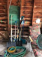 Group of shovels, rake, broom, hose, cord