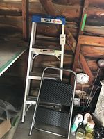 Both ladder and step stool leaning against wall