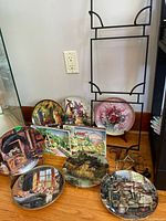 Group view showing seven round plates, two rectangular plaques and metal stand