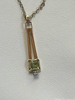 Pendant close-up showing peridot, diamond and gold design