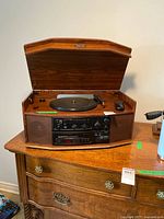 Overall view of Techsonic wood cabinet turntable stereo with lid open on wooden dresser