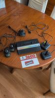 Console, two joysticks, cable and reference sheet on table