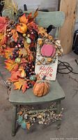 Full view of green chair with attached fall garland, sign, pumpkin
