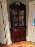 Full view of corner cabinet showing upper glass doors, lower cupboard, overall design