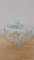 Side view of covered glass cake plate showing pedestal base and dome