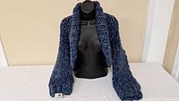 Front view of navy hand-knit shrug on mannequin