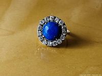 Front view showing lapis cabochon and halo of clear stones