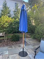 Closed blue umbrella on wood pole with base
