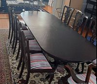 Top view of dark wood dining table flanked by multiple striped-seat chairs