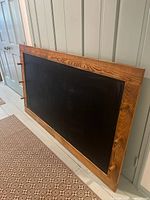 Full view of chalkboard framed in oak leaning against wall