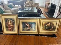 Front view of three framed prints leaning against sofa