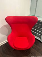 Front view of red egg-style lounge chair showing overall design and condition