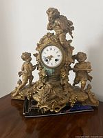 Front view showing cherub figures, ornate base and dial