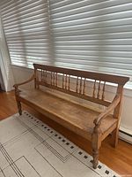 Front angled view of entire bench showing spindle back, seat, arms, legs