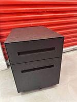 Front view showing two recessed-handle drawers and casters