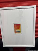 Full view of framed artwork showing white frame and mat with central print