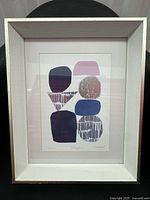 Full view of framed abstract print in white wooden frame