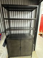 Front view showing full height shelving unit with three open tiers and lower cabinet