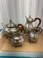 Full view of four hammered pewter pieces on tray