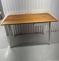 Front view of desk showing walnut top, white legs, raised side/back panels