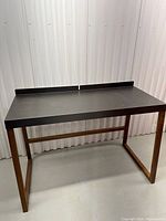 Front view of desk showing black top, walnut frame and back edge