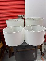 Front view of four white drum lamp shades in two sizes
