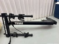 Side view of Thule rack showing main tube, folding hinge, cradle arms and branding
