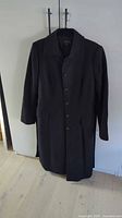 Front view of black Tahari coat on hanger showing button closure
