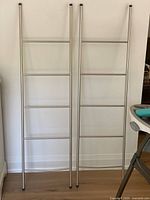 Full view of both metal towel ladders leaning against wall