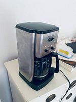 Front angled view of coffee maker showing stainless steel body and carafe