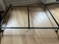 Full view of king bed frame showing rails, center support, casters