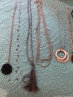 Left four necklaces showing tassel, multi-strand, double-circle pendant and plain chain