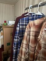 All three shirts hanging on hangers: burgundy, blue plaid, brown plaid
