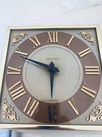 Front view of square Bulova wall clock showing dial, numerals, frame, hands