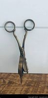 Brass candle wick trimmer scissors front view, finger loops and spike visible