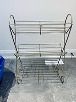 Front view of gold metal rack showing three shelves and curved sides