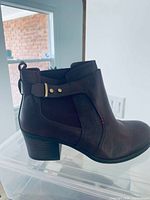 Side view of right boot showing color, heel, buckle strap, condition