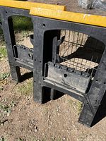 Two black plastic folding sawhorses with yellow tops, overall view