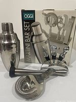 Opened Oggi martini bar set showing shaker, strainer, muddler, stand and tools