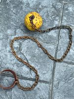 Full view of iron ball, chain and shackle on stone surface