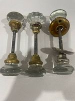 Front view of three antique glass door knob sets showing knob shapes and metal bases