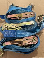 Three blue ratchet straps coiled with hooks and ratchets visible