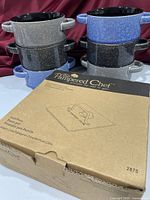 Six Mikasa bowls stacked beside boxed Pampered Chef grill press