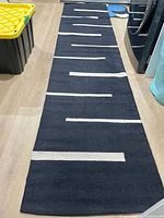 Full view of black runner rug with cream stripes on floor