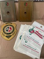 Overall lot showing two award plates, shield sign, and stack of promotional bags
