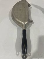 Closed view of cast-aluminum hinged pan showing side profile and one handle