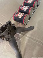 Cast iron tree stand and row of paint cans on cardboard surface