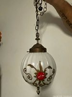 Full view of hanging pendant light showing glass globe, painted motif, hardware