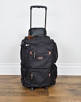 Front view of black Jaguar Sport Collection rolling duffel showing logo, zippered compartments and telescopic handle extended