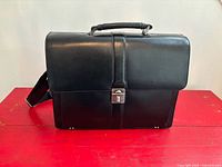 Front view of black leather Mancini briefcase with flap closed and top handle